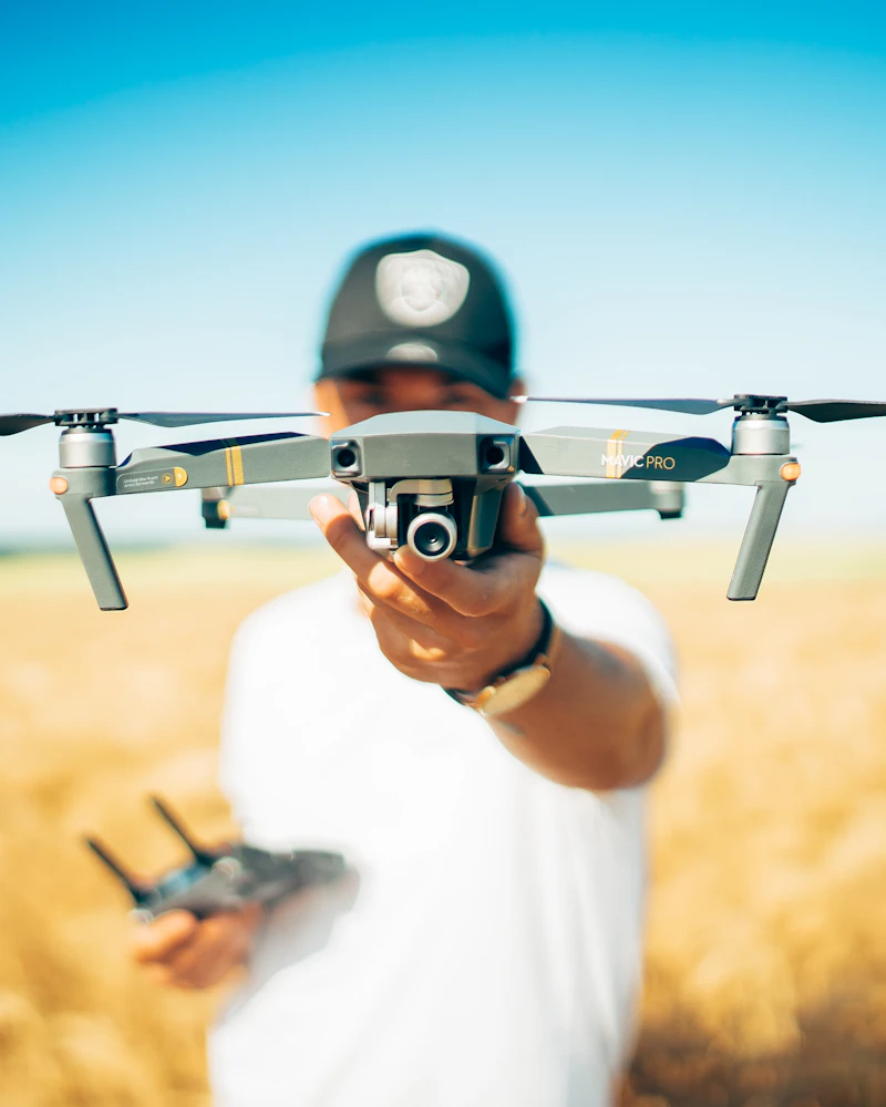 Piloto sosteniendo un dron frente a la cámara en un campo de trigo