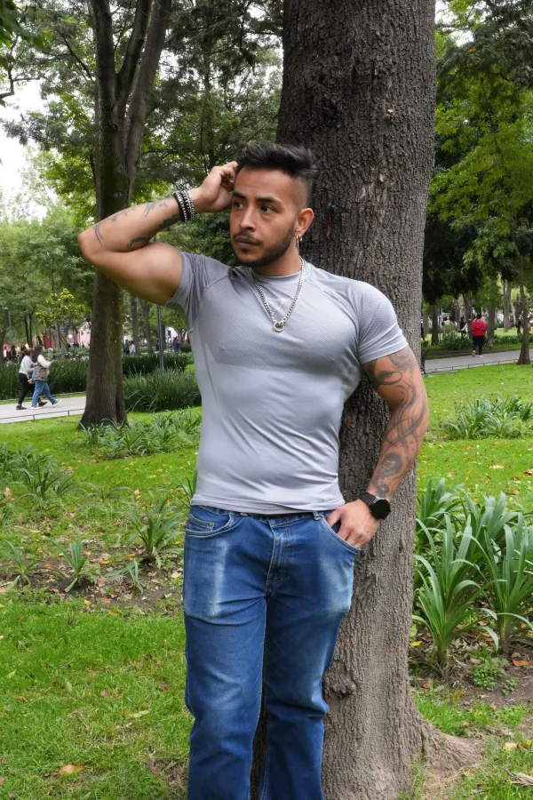 Hombre con playera gris junto a un árbol de la Alameda Central, con la mano detrás de la cabeza